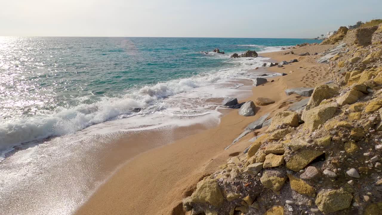 hermosa playa de arena mediterránea, maresme barcelona, san pol de mar, con rocas y mar tranquilo y turquesa, costa brava