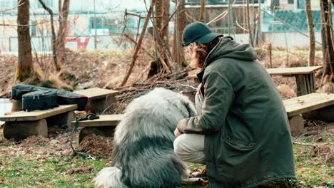 Hier-Sieht-Man-Einen-Jungen-Mann-Mit-Schwarzer-Mütze,-Der-Liebevoll-Seinen-Flauschigen-Hund-Streichelt