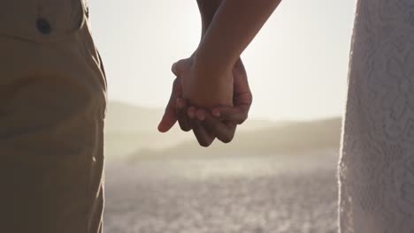 Focus-on-African-American-couple-holding-their-hands-at-beach