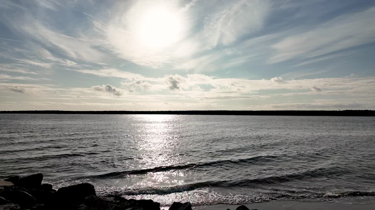 Vakkert, solfylt sjølandskap i Laguna Beach, California, med sollys som reflekteres i havet og bølger som forsiktig ruller mot land