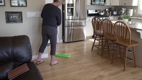 Senior-woman-sweeping-and-dusting-her-hardwood-oak-floors---tilt-up