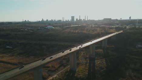 daytime traffic at galati viaduct bridge on sunny day in galati, romania. steel manufacturing plant in distance. wide aerial shot