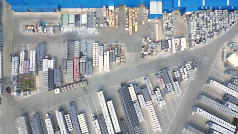 Forklift-truck-driver-in-warehouse-driving-between-rows-of-shelving-with-stacks-of-boxes-and-packaging-materials