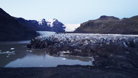 aerial: revealing glaciers serpentine path with deep crevasses and jagged ice formations, evidence of the impact climate change has on the constant movement and transformation of this natural wonder