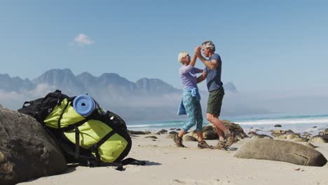 senior hiker couple dancing on the beach while hiking.