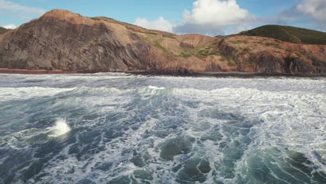 aerial 4k drone coastal shot of heavy waves at praia da cordoama hidden cliff coastline near the algarve region of portugal