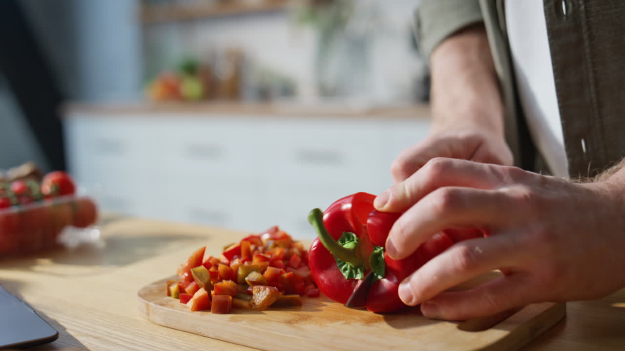 Cook hands slicing pepper on chopping board home kitchen closeup. Man preparing