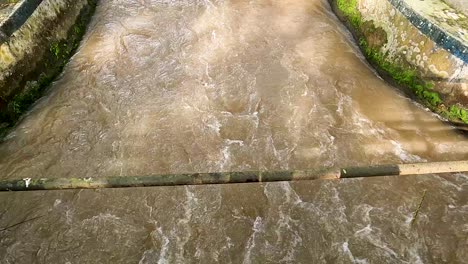static view of brown water flowing rapidly in manggis river, indonesia