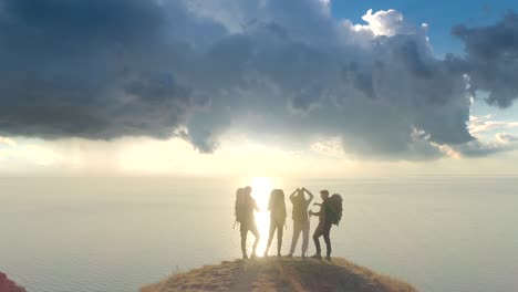 the four people standing on the mountain cliff against the beautiful background