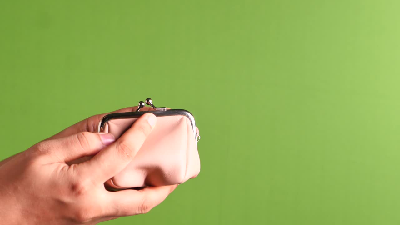 las manos de la mujer poniendo monedas en el bolso rosa