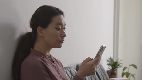 female candidate wearing suit in office waiting for job interview looking at mobile phone 2