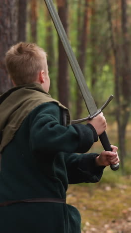 peasant boy runs with sword in his hands through forest, historical reconstruction, subculture, children's camp