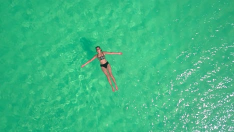 Mujer-Flotando-En-Un-Océano-Tranquilo,-Cálido-Y-Tropical.-Aéreo