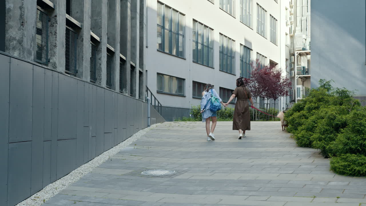 Two women walking their dog in the city