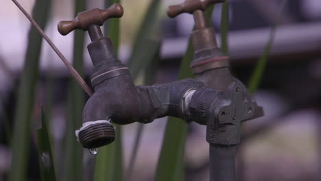 Wassertropfen,-Die-Aus-Einem-Messinghahn-Austreten,-Um-Den-Klempnerband-Gewickelt-Ist