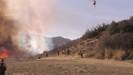 firefighters look on as a blaze burns out of control in california