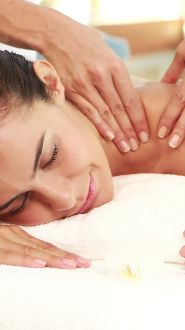 Massør giver massage til afslappende kvinde