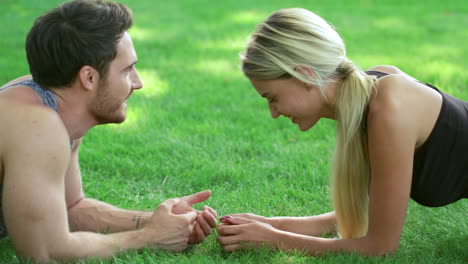 Fitness-Frau-Trainiert-Plankenübung-Gemeinsam-Mit-Dem-Trainer,-Der-Auf-Gras-Im-Park-Liegt