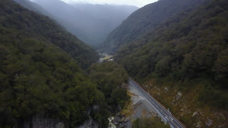 aerial shot of road with rocky cliff face and green forest