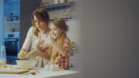 young good looking mother and her cute daughter trying to clean their hands from a daugh while cooking together in the cozy kitchen. inside