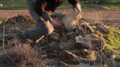 joven tropieza y casi se cae mientras lleva una gran roca al aire libre