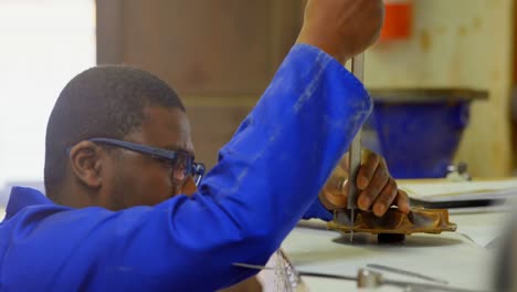 worker using caliper at table in foundry workshop 4k