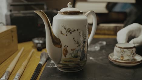 antique expert inspects china porcelain tea-set with gloved hands