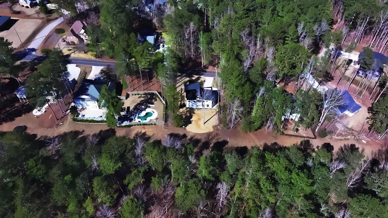 Small American neighborhood called Fairfield Plantation with luxury homes and swimming pool between green trees. Sunny summer day in Villa Rica, Georgia, USA. Aerial top down.