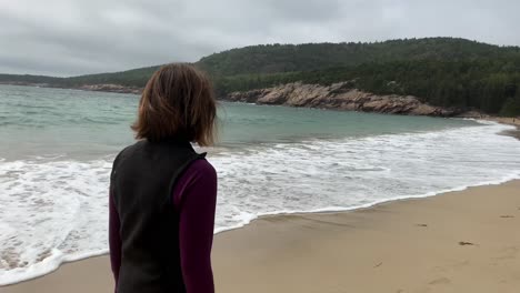 4k mujer camina pensando en la playa de arena en el parque nacional acadia