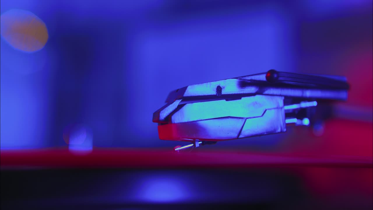 Pladespillerpickup sænkes ned på vinylplade i neonlys
