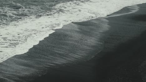 Antenne-Von-Wellen,-Die-An-Einem-Schwarzen-Sandstrand-In-Island-Zusammenbrechen