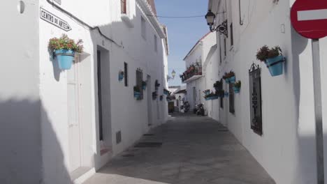 a super slow motion of a classic spanish white alleyway with blue flowerpots on a clear summer day