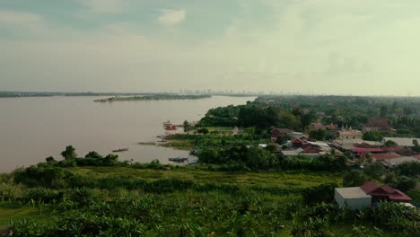 rising drone view over mekong river near phnom penh, tang island in the near distance and the city skyline beyond