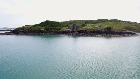 a low-flying drone shot of an old and historic cemetery on a small and isolated peninsula in ireland