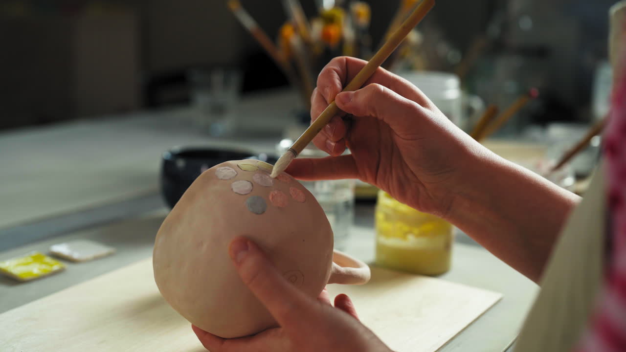 The Person is Painting Circular Patterns on a Ceramic Cup Using a Fine Brush - Close Up