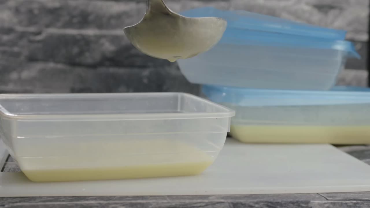Servindo sopa cremosa em um recipiente de plástico com concha