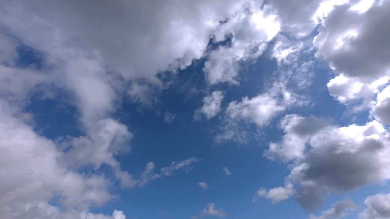 Dynamic timelapse of large clouds drifting from west to east, forming weather front across sky. Fast cloud movement overhead