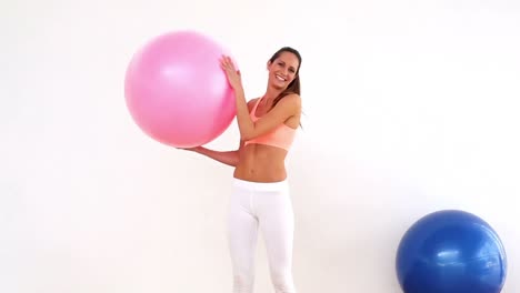 modelo en forma sosteniendo una pelota de ejercicio y sonriendo a la cámara