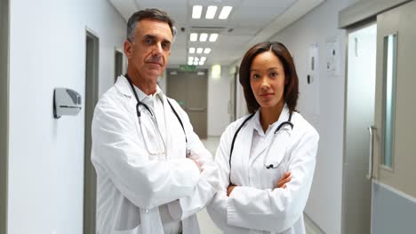 portrait of doctors standing with arms crossed in corridor