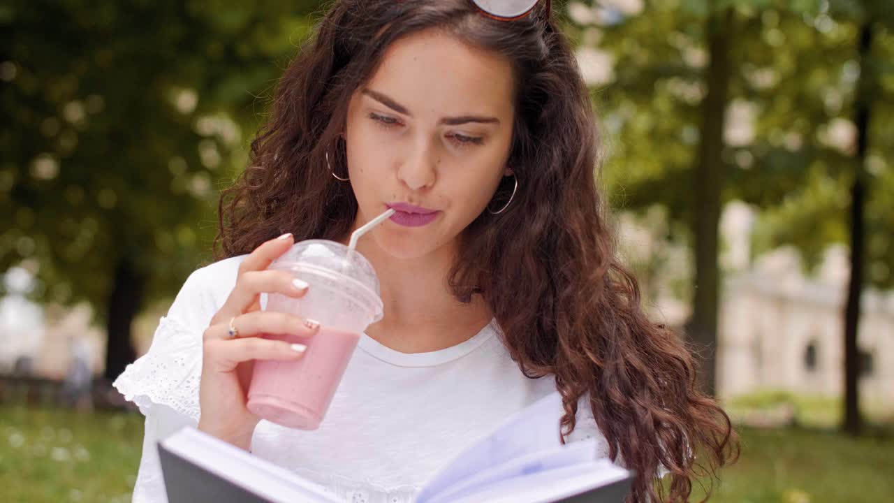 una mujer joven leyendo un libro en el parque.