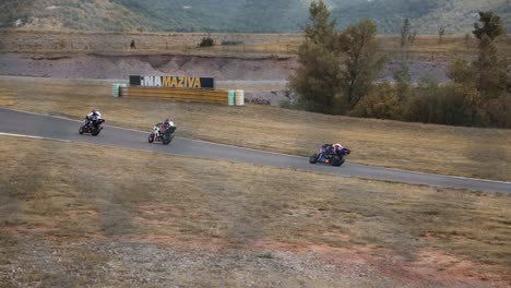 motocycle drivers racing on a track through fence