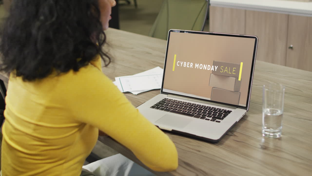 Biracial woman at table using laptop, online shopping on cyber monday sale day, slow motion