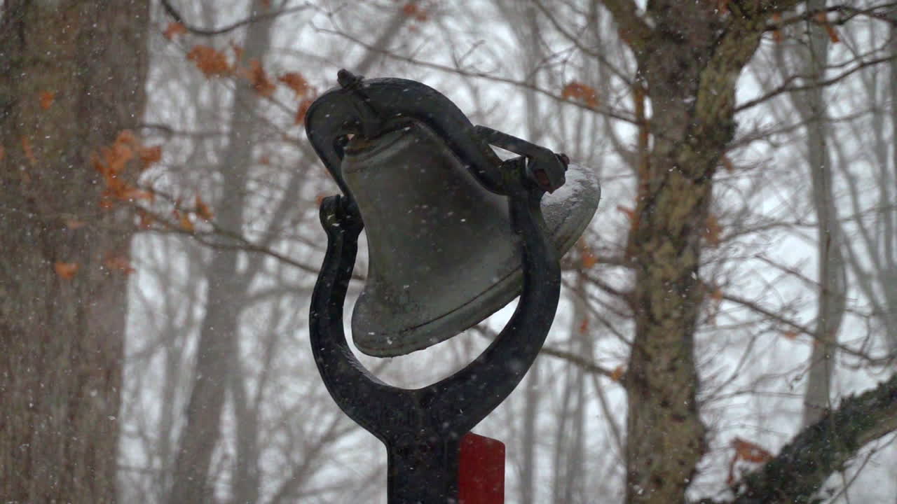 nevadas en cámara lenta en un día de invierno cubierto de nieve con una campana al aire libre en segundo plano