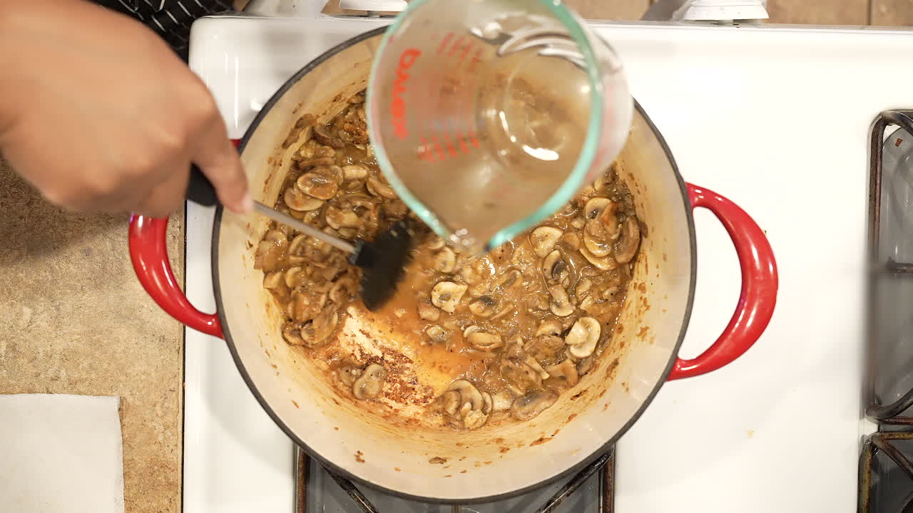 agregando jerez de cocina a los champiñones salteados en una olla en la estufa para obtener una deliciosa sopa casera - vista superior de la serie de arroz salvaje