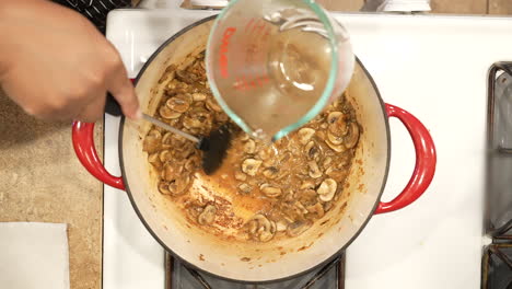 adding cooking sherry to sauteed mushrooms in a pot on the stove for a delicious homemade soup - overhead view wild rice series