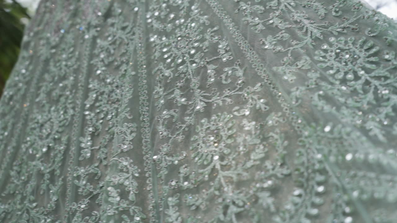 An elegant Indian reception gown glitters beside tropical palm leaves, slow motion