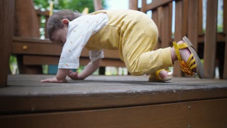 eurasian baby girl climb and crawl on stairs at playground. - close up, behind