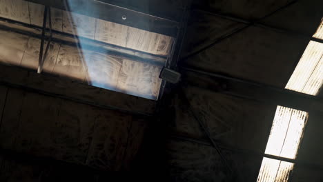 sun light gliding from rooftop to interior of wooden building with rays, flares and dust particles in slowmo