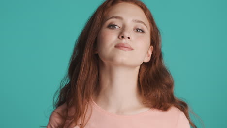 Redheaded-girl-in-front-of-camera-on-turquoise-background.