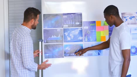 Side-view-of-young-mixed-race-male-executives-discussing-over-graph-in-modern-office-4k